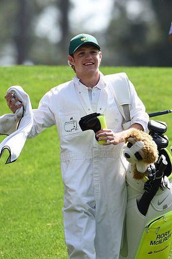 Niall Horan caddies for Rory McIlroy during the Par 3 Contest at the Masters