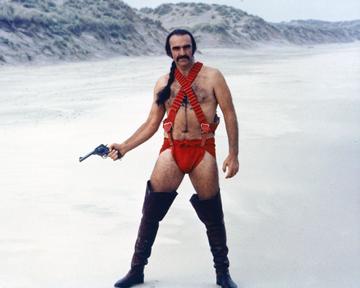 Sean Connery, British actor, holding a handgun while wearing thigh-high boots and red costume, with his hair in a pony tail, standing in a snowy landscape in a publicity portrait issued for the film, 'Zardoz', 1974. The science fiction film, directed by John Boorman, starred Connery as 'Zed'. (Photo by Silver Screen Collection/Getty Images)
