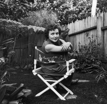 Circa 1956:  American actor Betty White sits in a canvas chair with her name written on the back, looking over her shoulder in a backyard garden.  (Photo by Hulton Archive/Getty Images)
