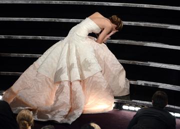 Actress Jennifer Lawrence trips on her dress while making her way to the stage after winning the Best Actress award for "Silver Linings Playbook" during the Oscars on February 24, 2013 in Hollywood, California.  (Photo by Kevin Winter/Getty Images)