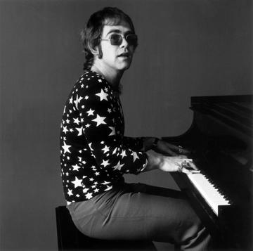 7th November 1970:  Portrait of British-born musician Elton John playing piano while wearing sunglasses and a shirt covered in stars.  (Photo by Jack Robinson/Hulton Archive/Getty Images)