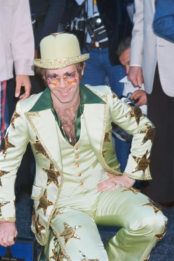 English singer-songwriter and pianist Elton John is honoured with a star on the Hollywood Walk of Fame, at 6915 Hollywood Boulevard, Los Angeles, 23rd October 1975. He is wearing a suit emblazoned with the names of stars, including his own. (Photo by Maureen Donaldson/Getty Images)